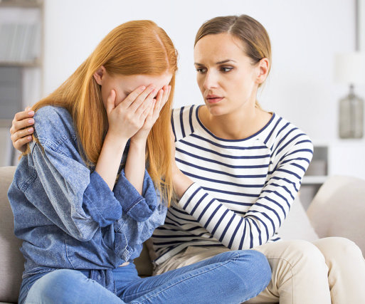 a young lady crying while her friend is comforting her