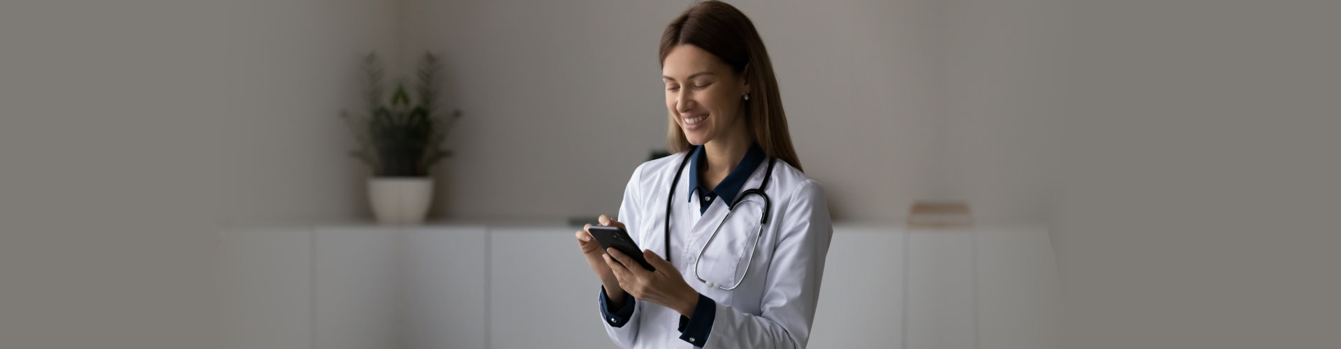 smiling young lady doctor pediatrician family therapist hold cellphone make call to patient to tell good news